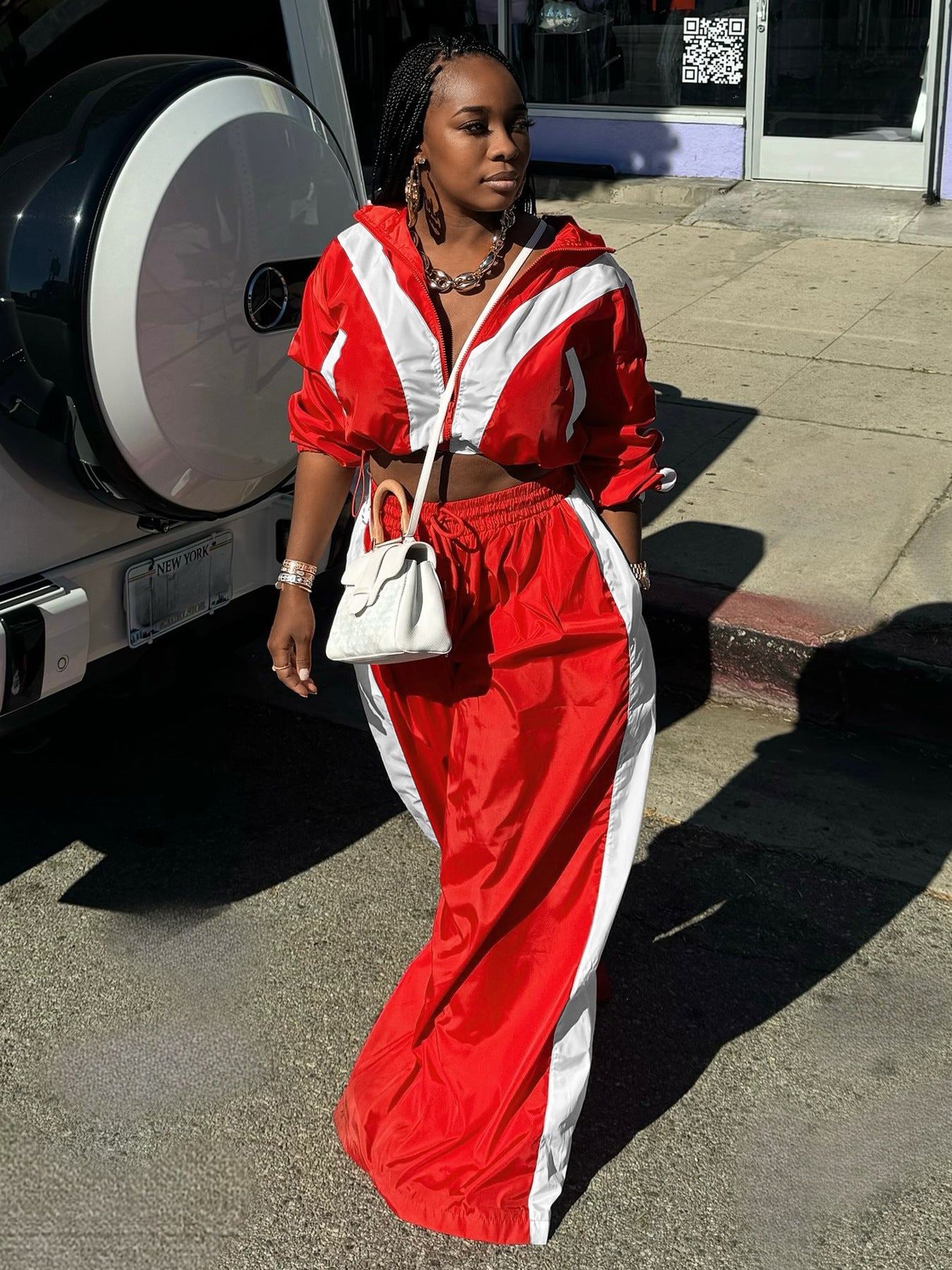 Person wearing a red and white outfit standing on a street.
