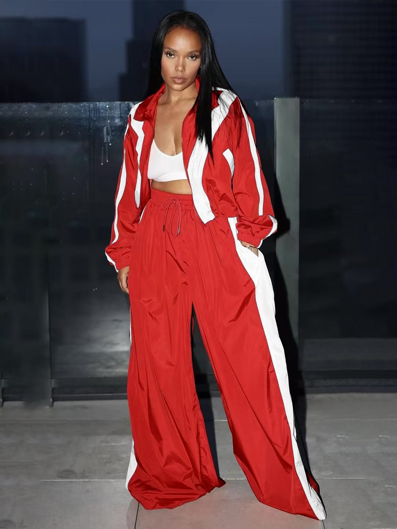 Person wearing a red tracksuit with white accents on a dark background